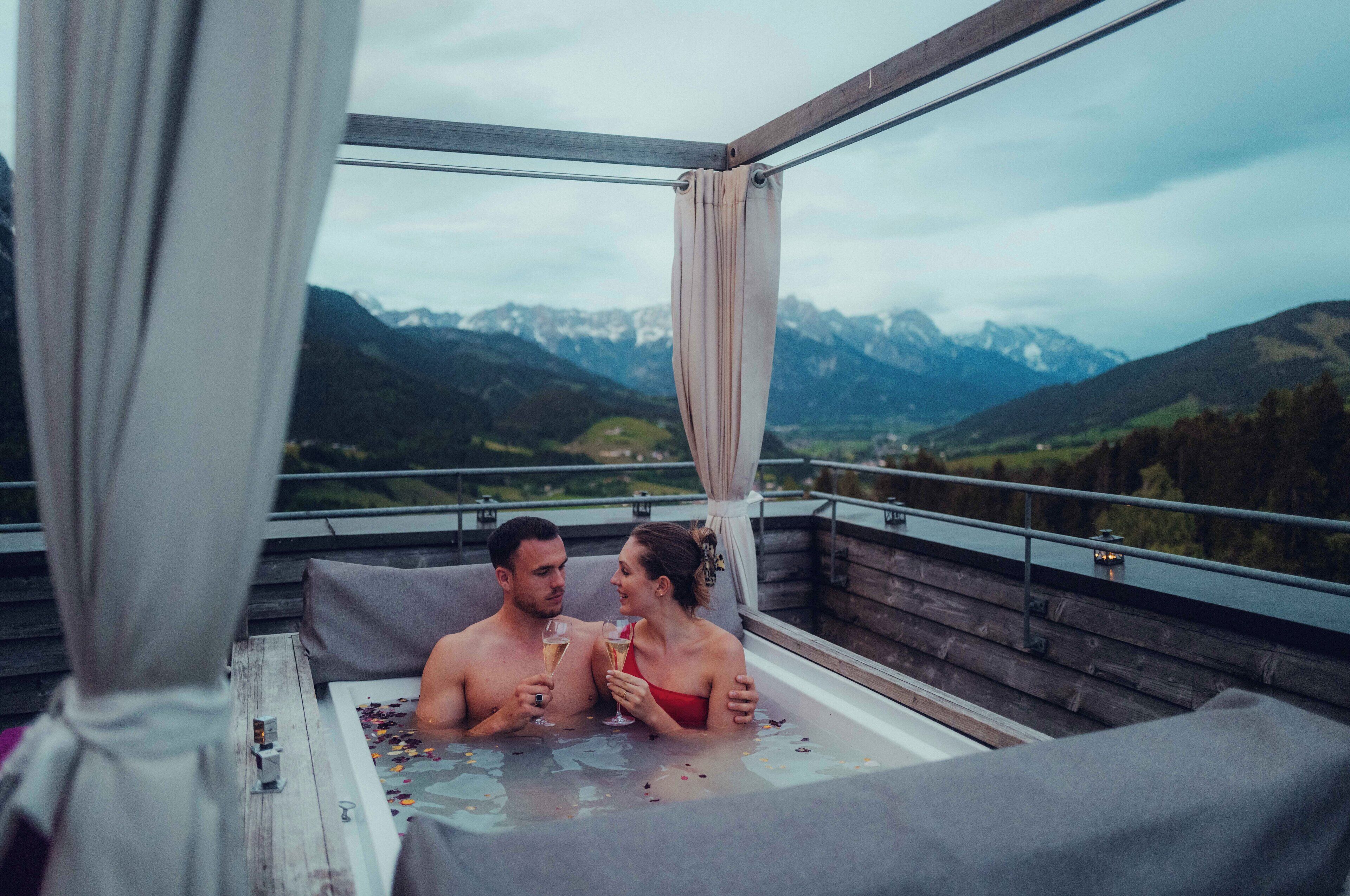 Ein Paar entspannt in einer Whirlpool mit Blick auf die Berge.
