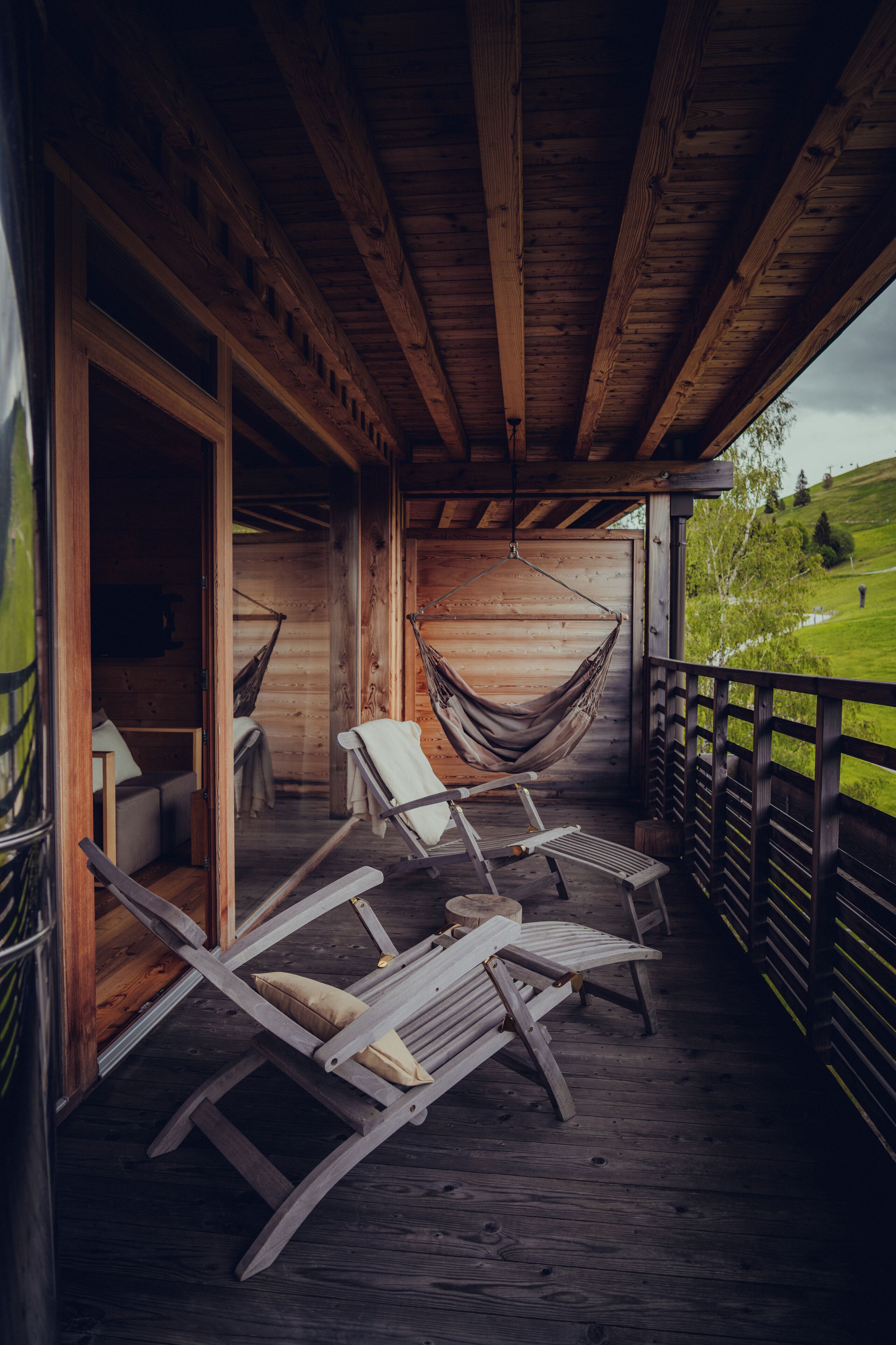 A wooden cabin with a porch featuring two rocking chairs and a hammock.