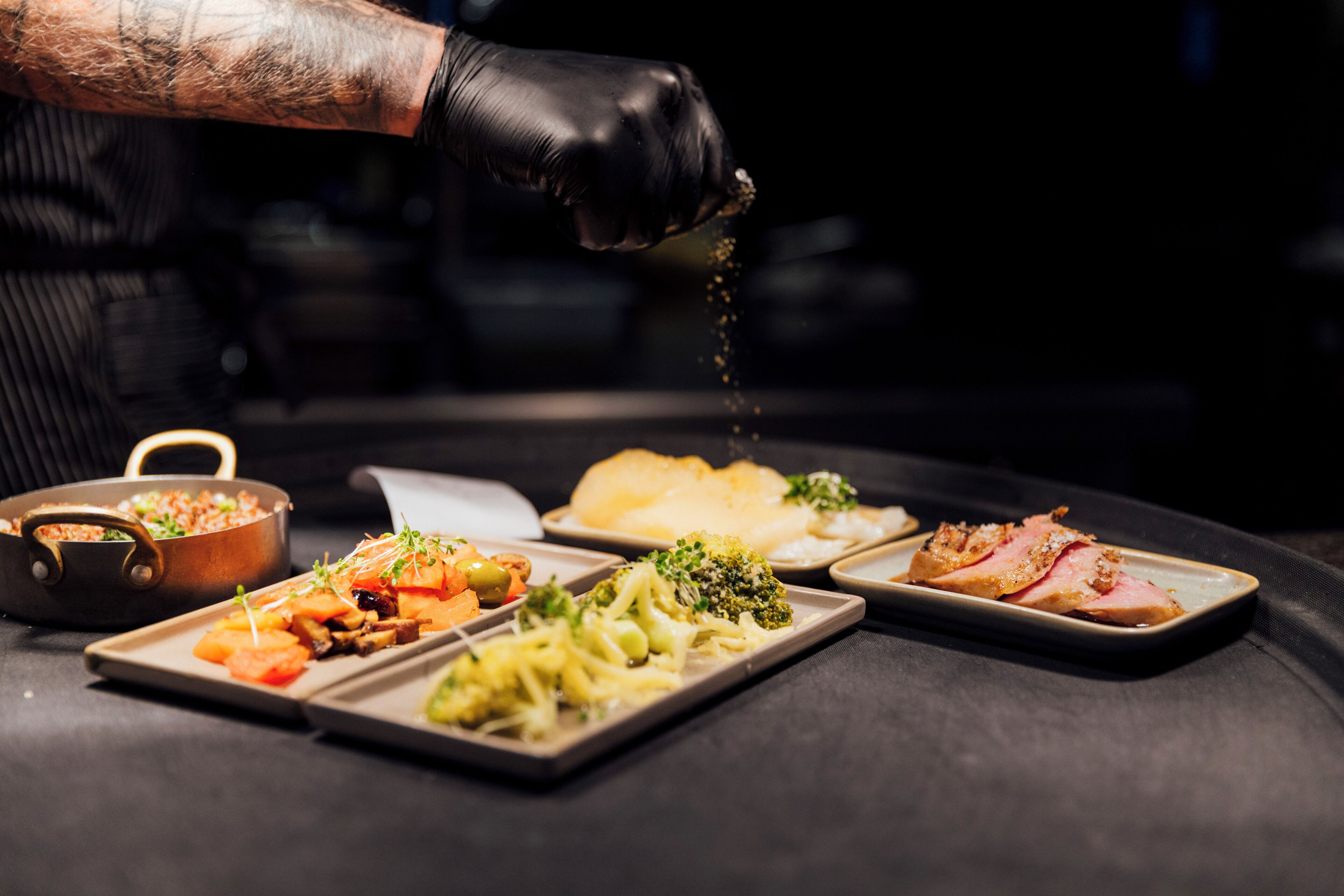 Un chef sazonando comida con una especia.