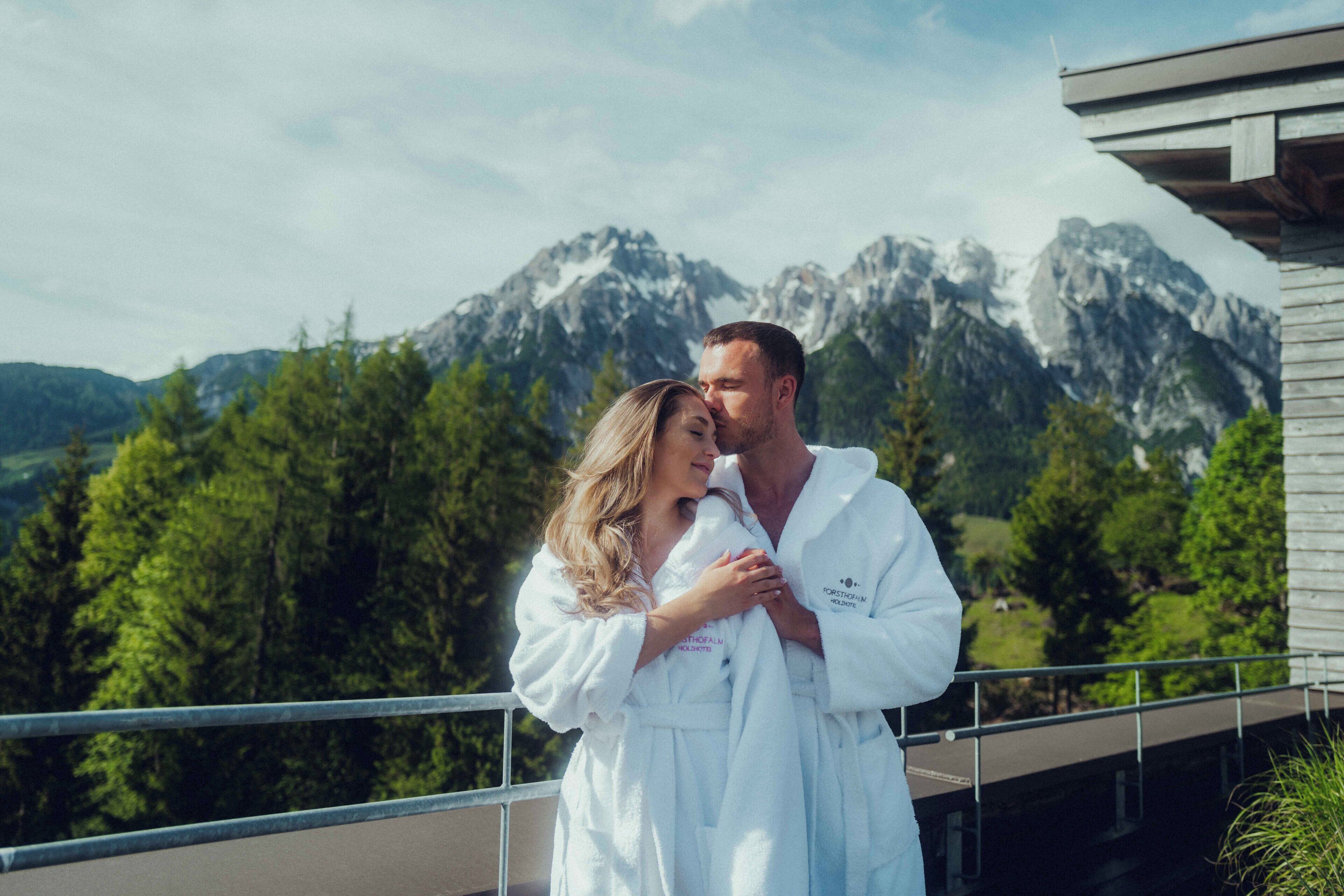 A couple in white robes on a balcony with a mountain view.