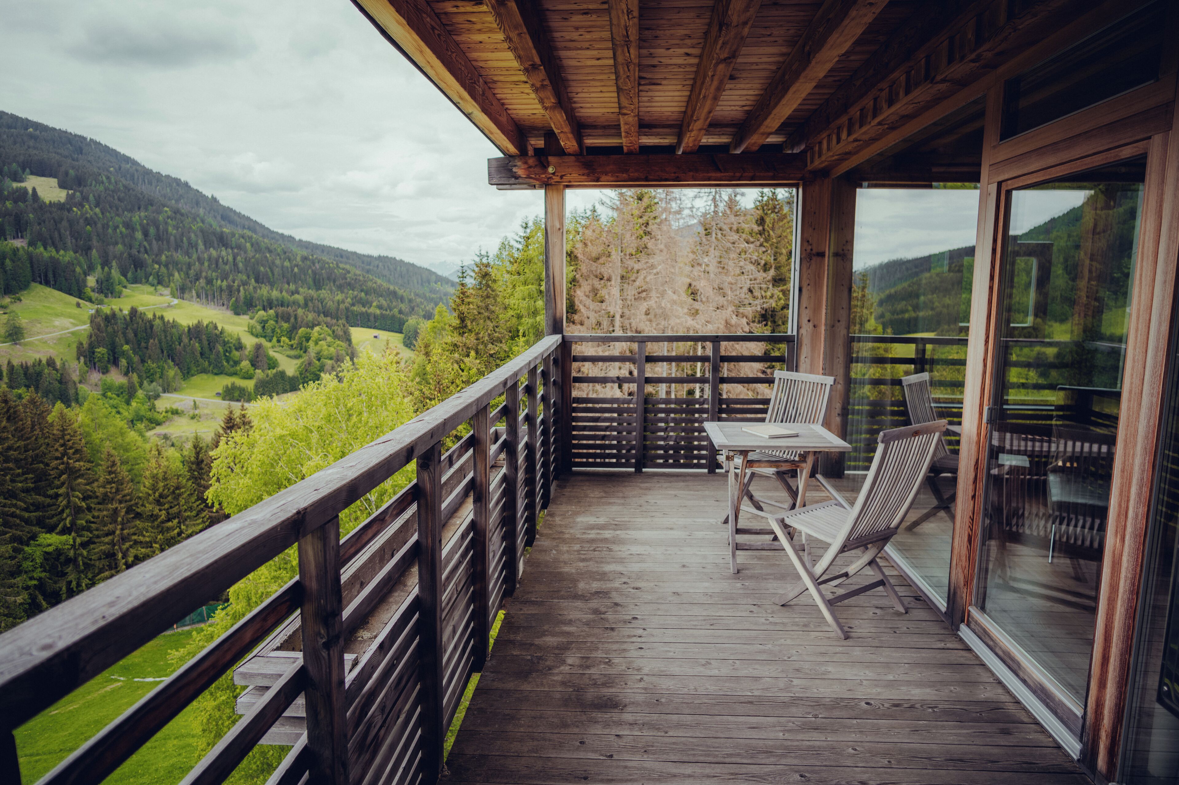 Una terraza de madera con una mesa y sillas, con vistas a un paisaje montañoso.