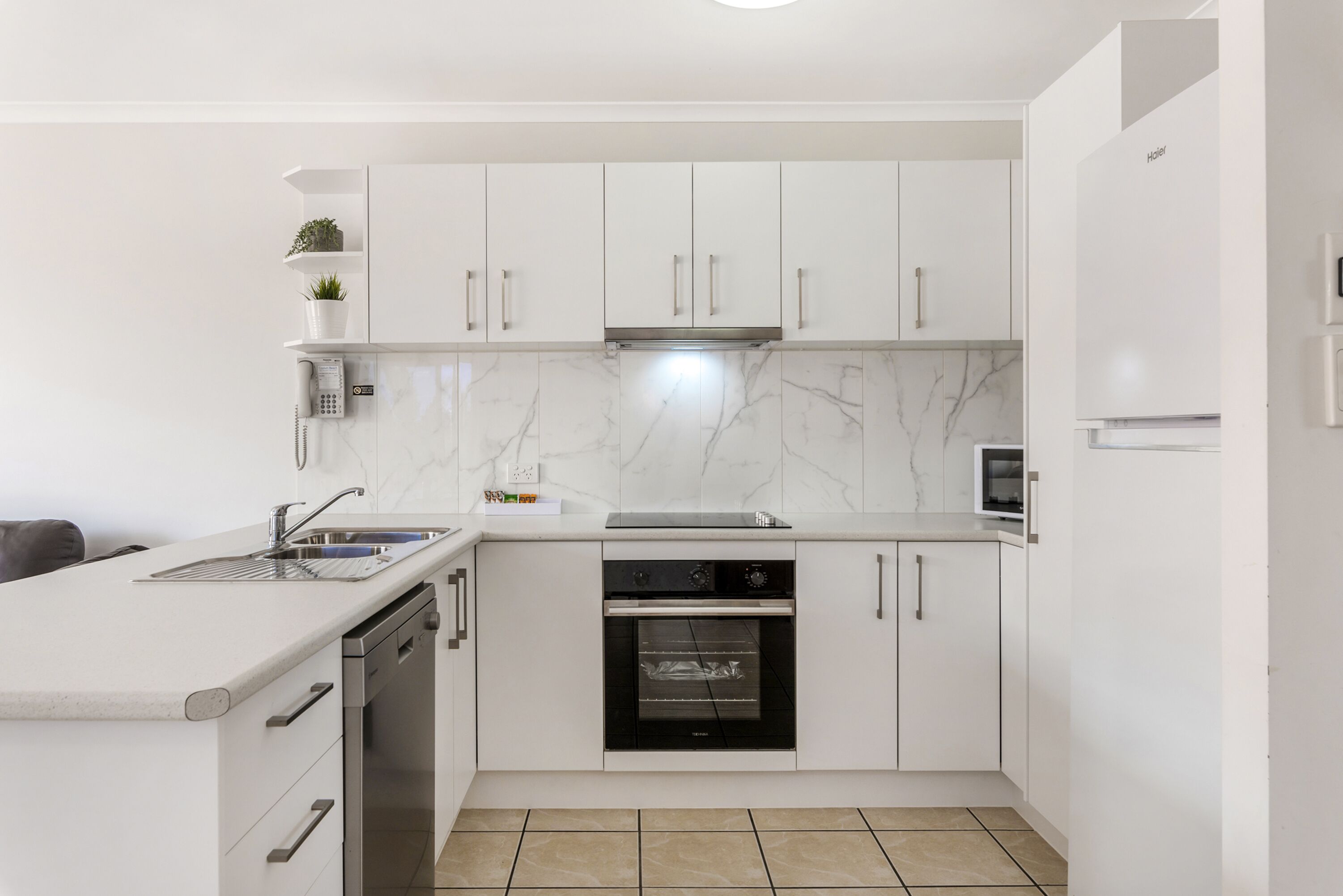 A modern kitchen with white cabinets, a built-in oven, and a stainless steel dishwasher.