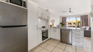 A modern kitchen with stainless steel appliances, white cabinetry, and a view to the outside. - Coolum Beach Getaway Resort (Coolum Beach)