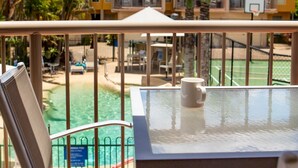 A poolside view with a table and chairs, a basketball court, and a building with balconies. - Coolum Beach Getaway Resort (Coolum Beach)