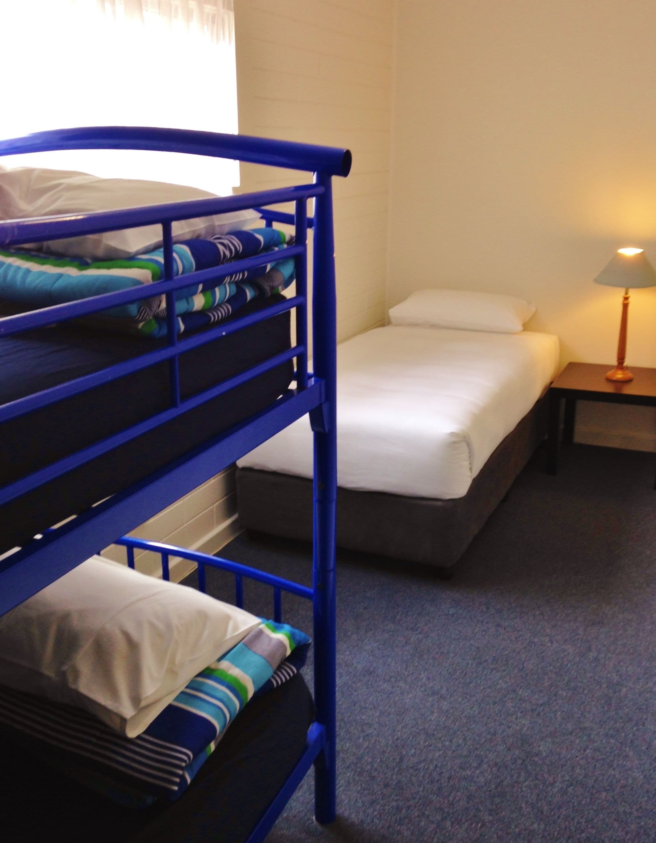 A bunk bed room with a nightstand and a lamp.
