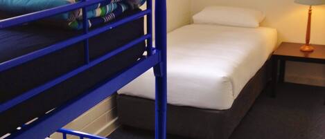 A bunk bed room with a nightstand and a lamp.