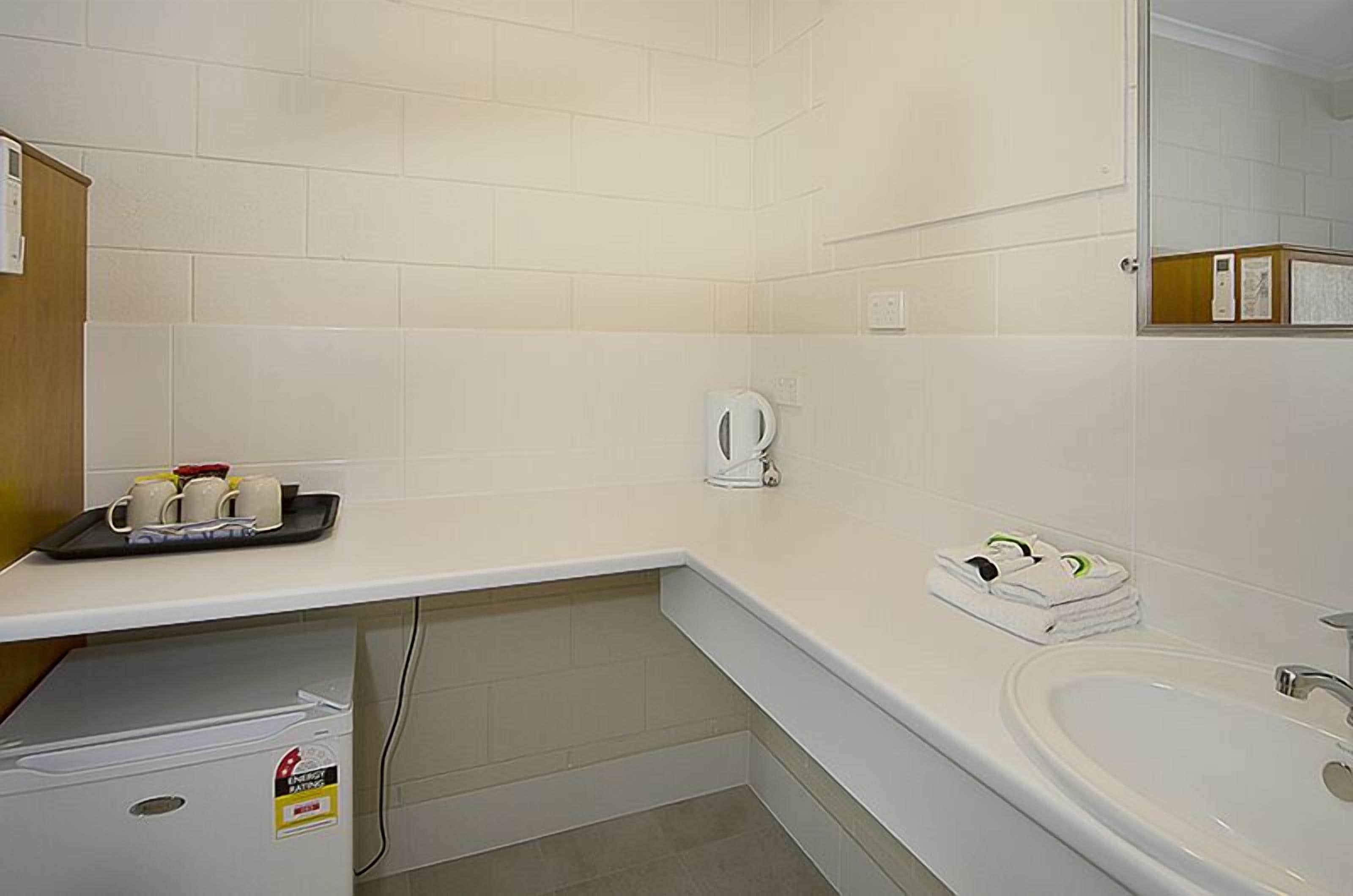 A hotel bathroom with a white sink, a mirror, and a coffee maker on the countertop.