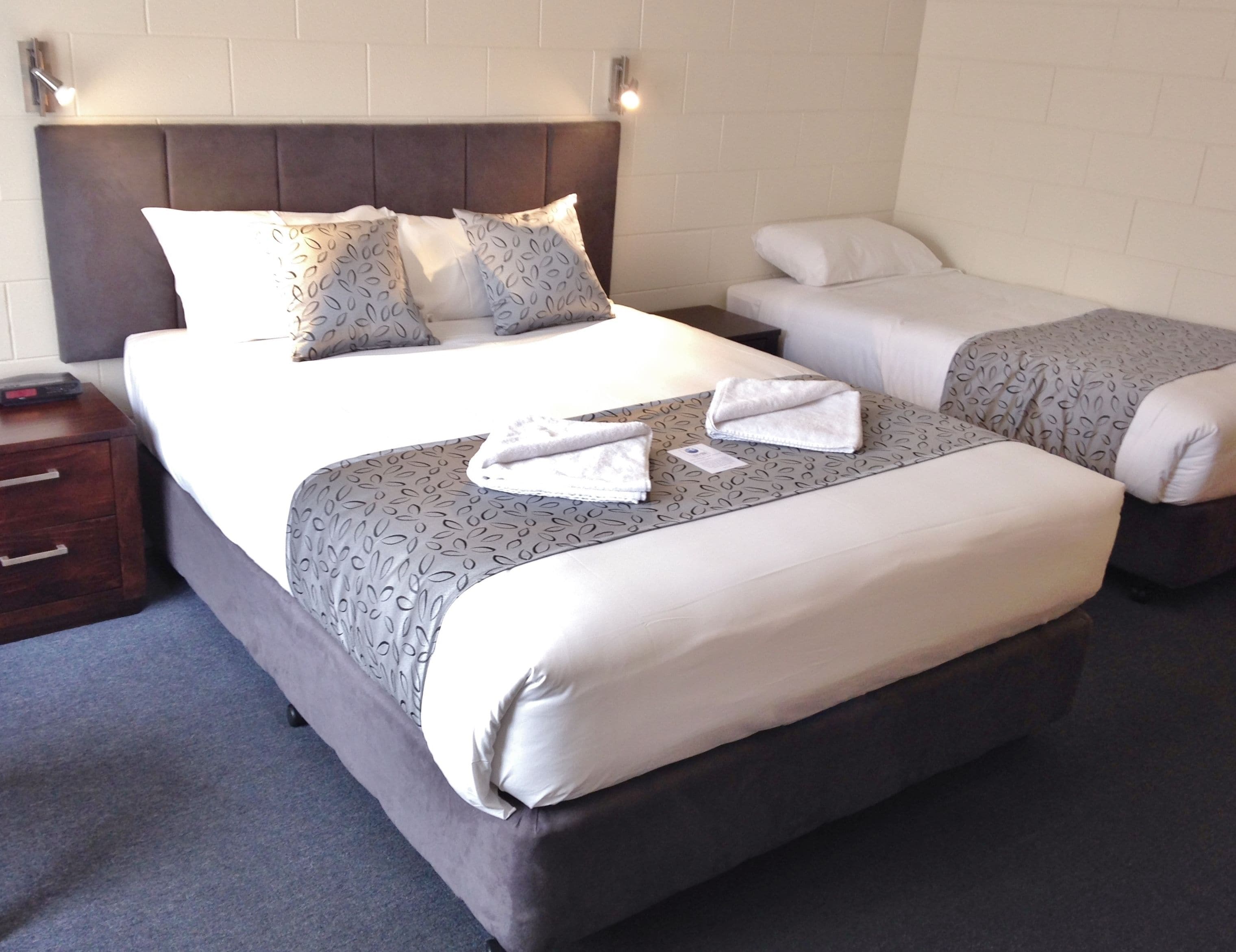 Ein Hotelzimmer mit einem großen Bett, zwei Nachttischen und einem Kopfteil.