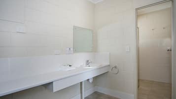 Un baño con lavamanos blanco, espejo y paredes con azulejos.