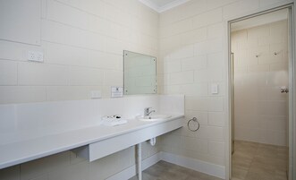 Un baño con lavamanos blanco, espejo y paredes con azulejos.