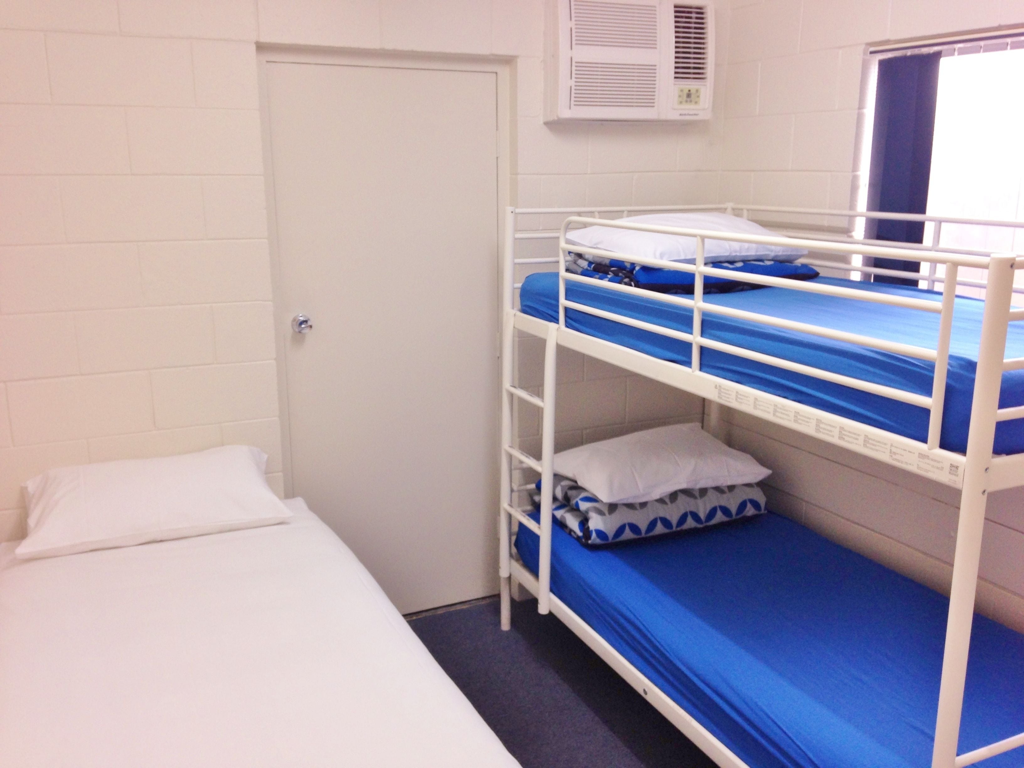 Un dormitorio con literas, una cama individual, una puerta y una ventana con cortinas.