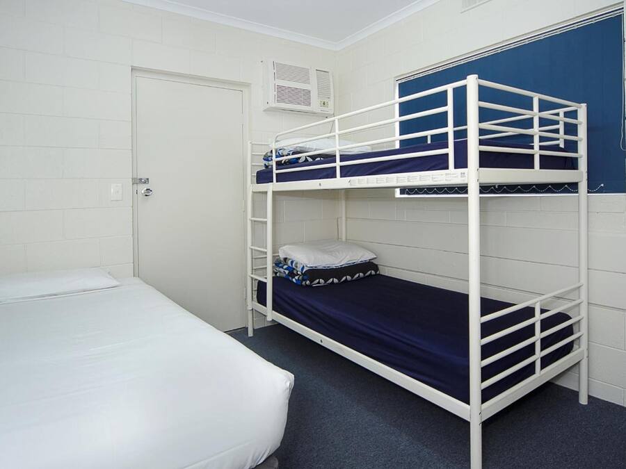 A bunk bed room with a white door, a white air conditioning unit, and a blue curtain.