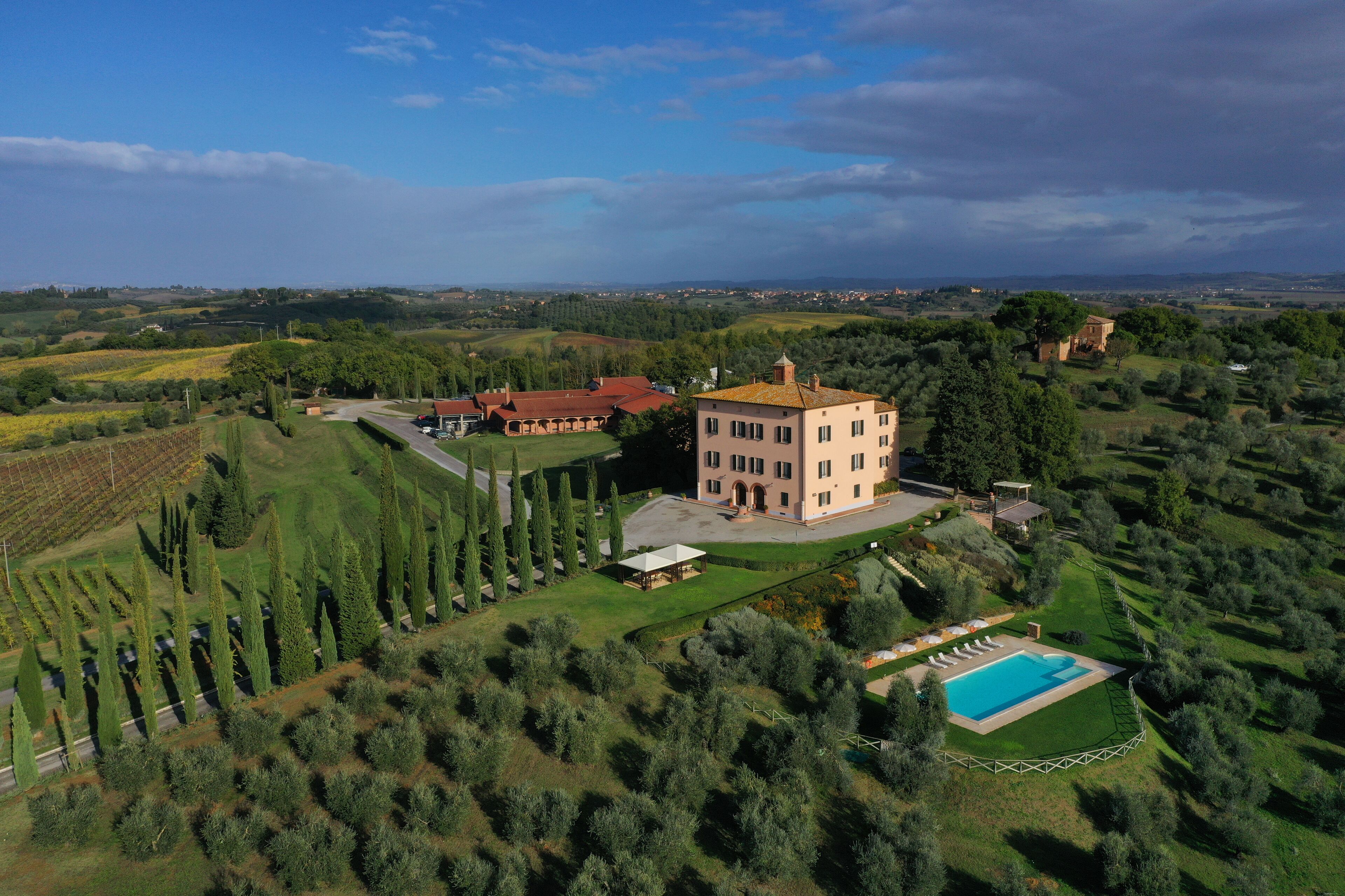 A large estate with a central building, a swimming pool, and surrounding landscaped gardens.