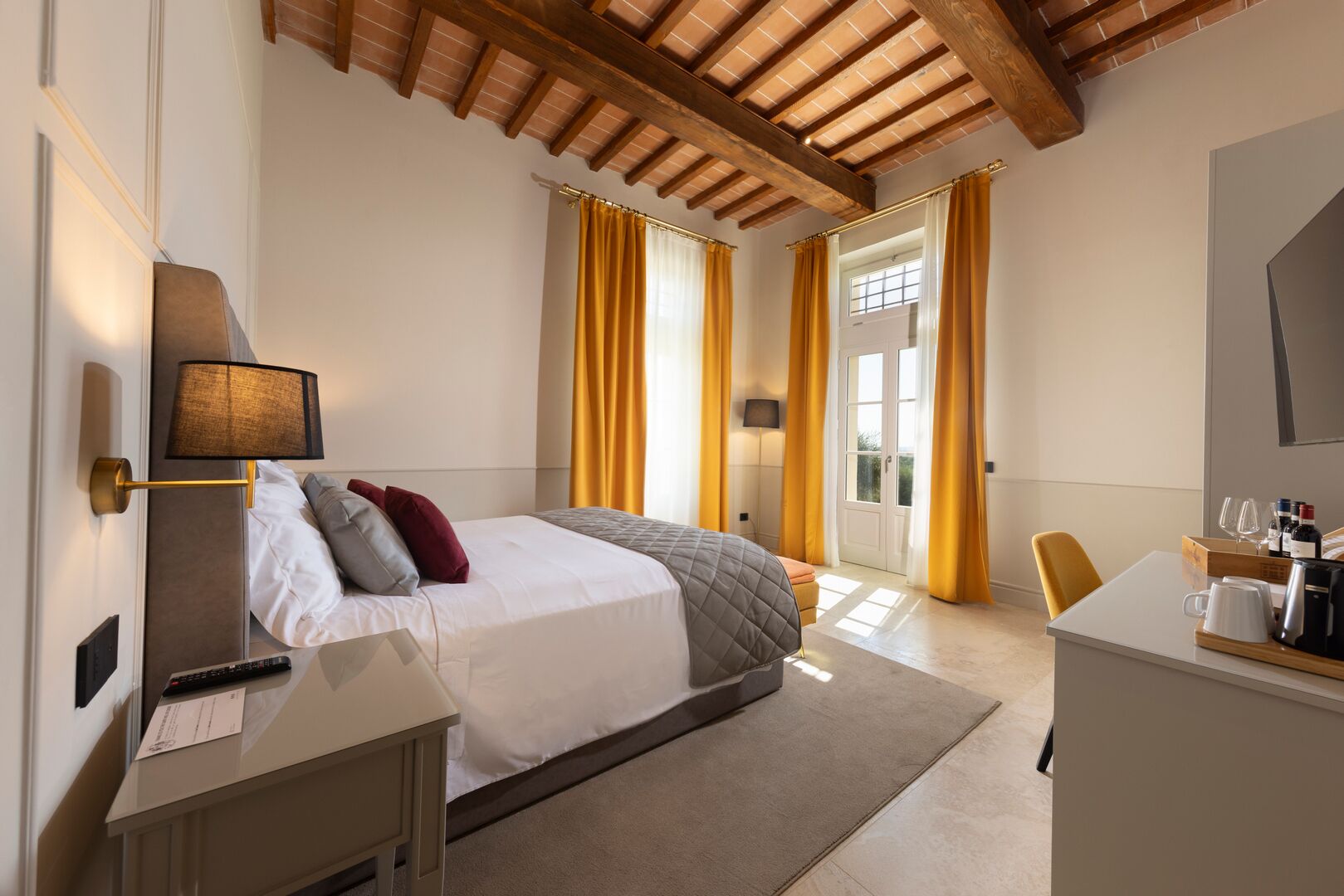 A hotel room with a bed, bedside table, desk, and a mirror.