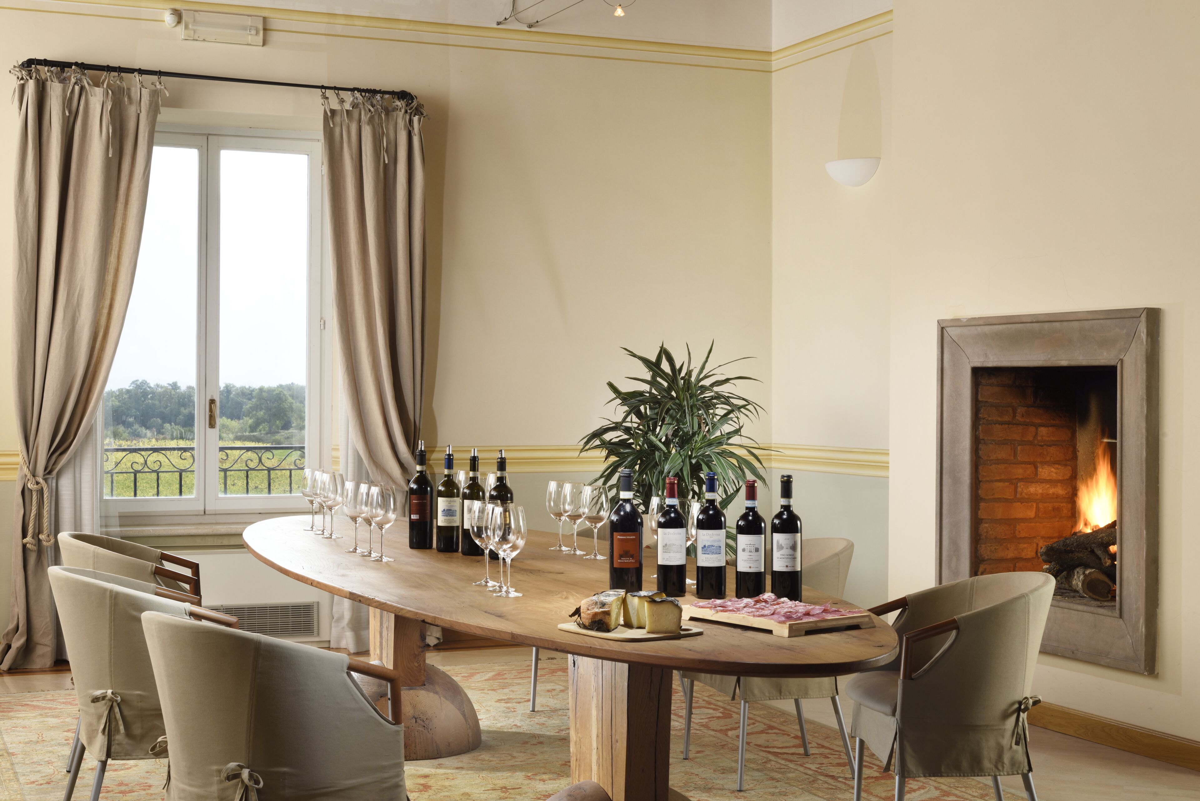 A dining area with a wooden table, wine bottles, glasses, and a fireplace.