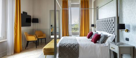 A modern bedroom with a four-poster bed, a desk, and two chairs.