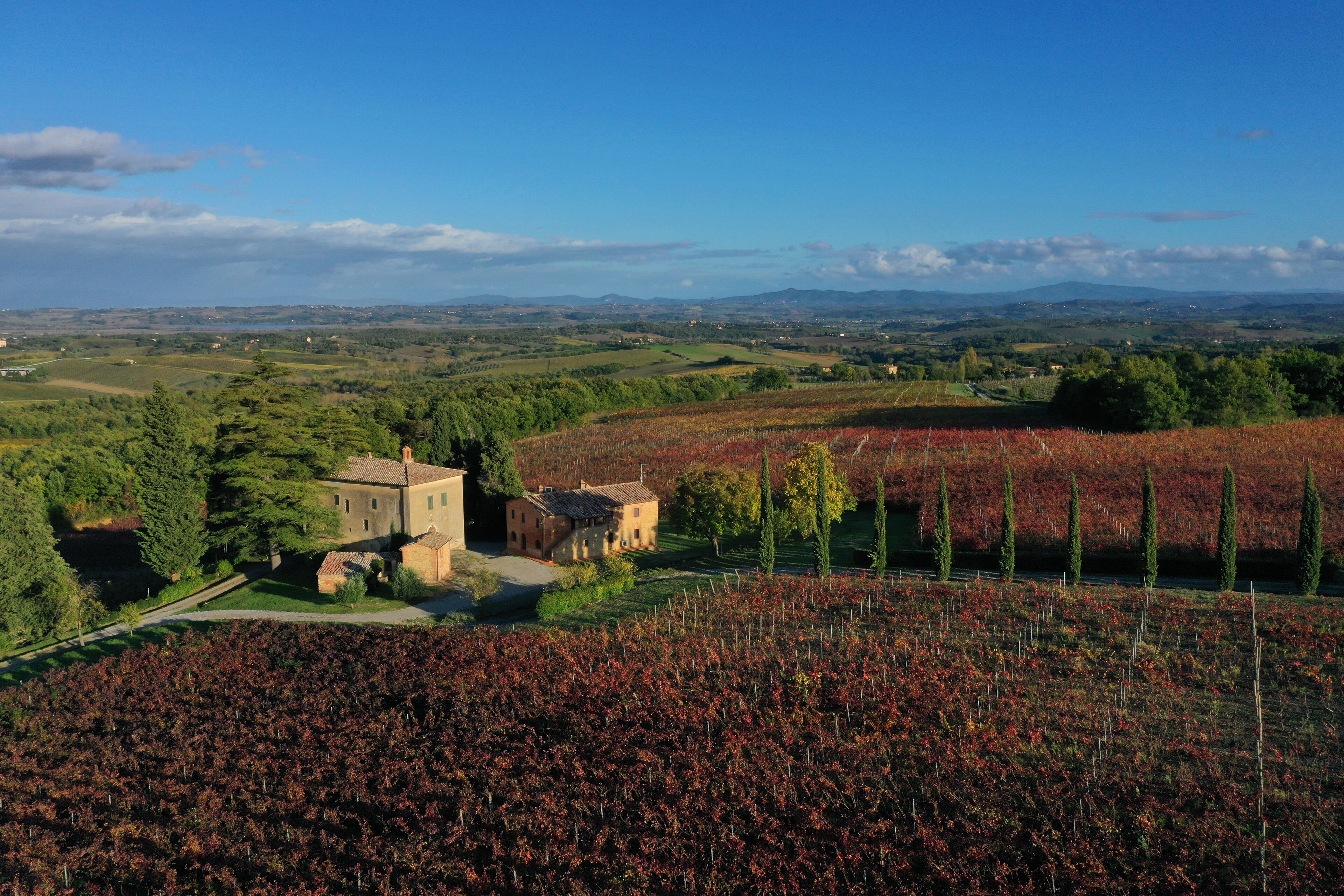 Un paysage rural avec un bâtiment en pierre entouré d’arbres et de champs.