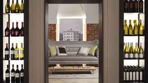 A cozy room with a sofa and a coffee table, surrounded by shelves of wine bottles. - Relais Villa Grazianella - UNA Esperienze (Montepulciano)
