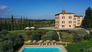 A large building with a pool, surrounded by greenery and trees. - Relais Villa Grazianella - UNA Esperienze (Montepulciano)
