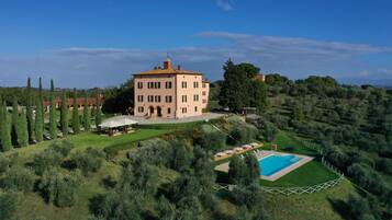 A large, multi-story building with a symmetrical facade, surrounded by well-manicured gardens and a swimming pool.
