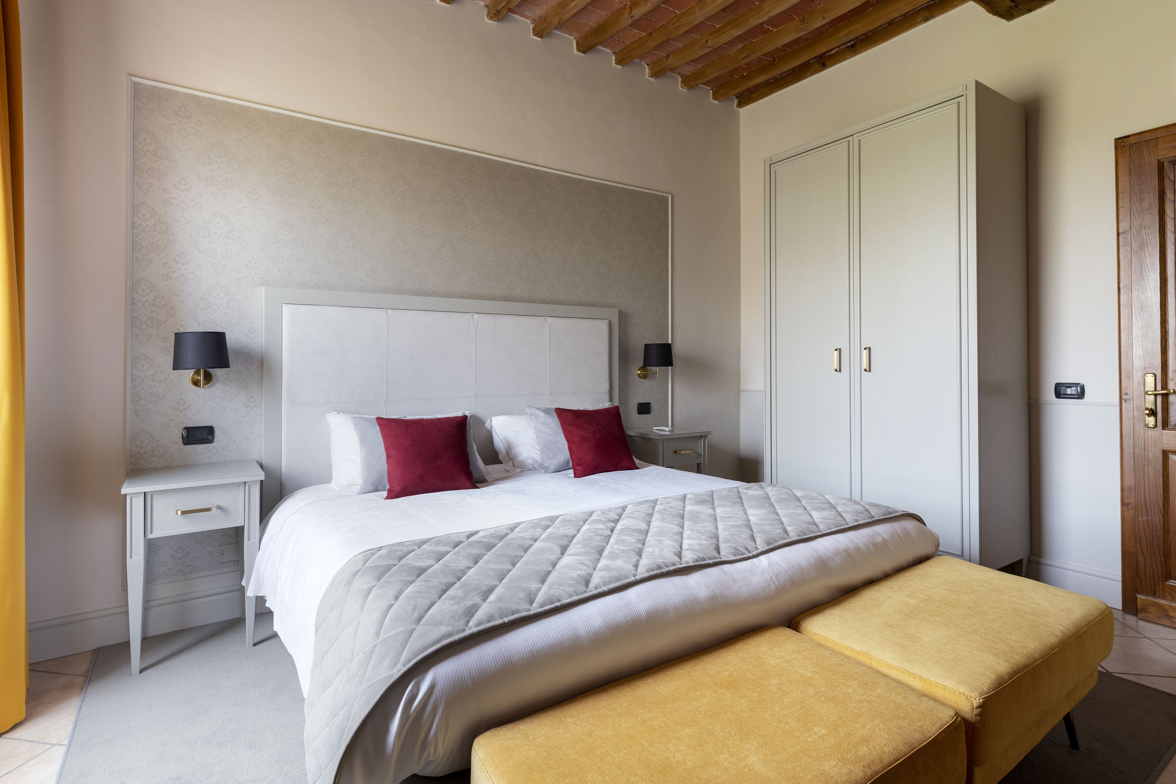 Ein Schlafzimmer mit einem großen Bett, zwei Nachttischen, einem Kleiderschrank und einer Bank.