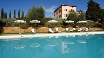 Una piscina al aire libre, sillones reclinables de piscina