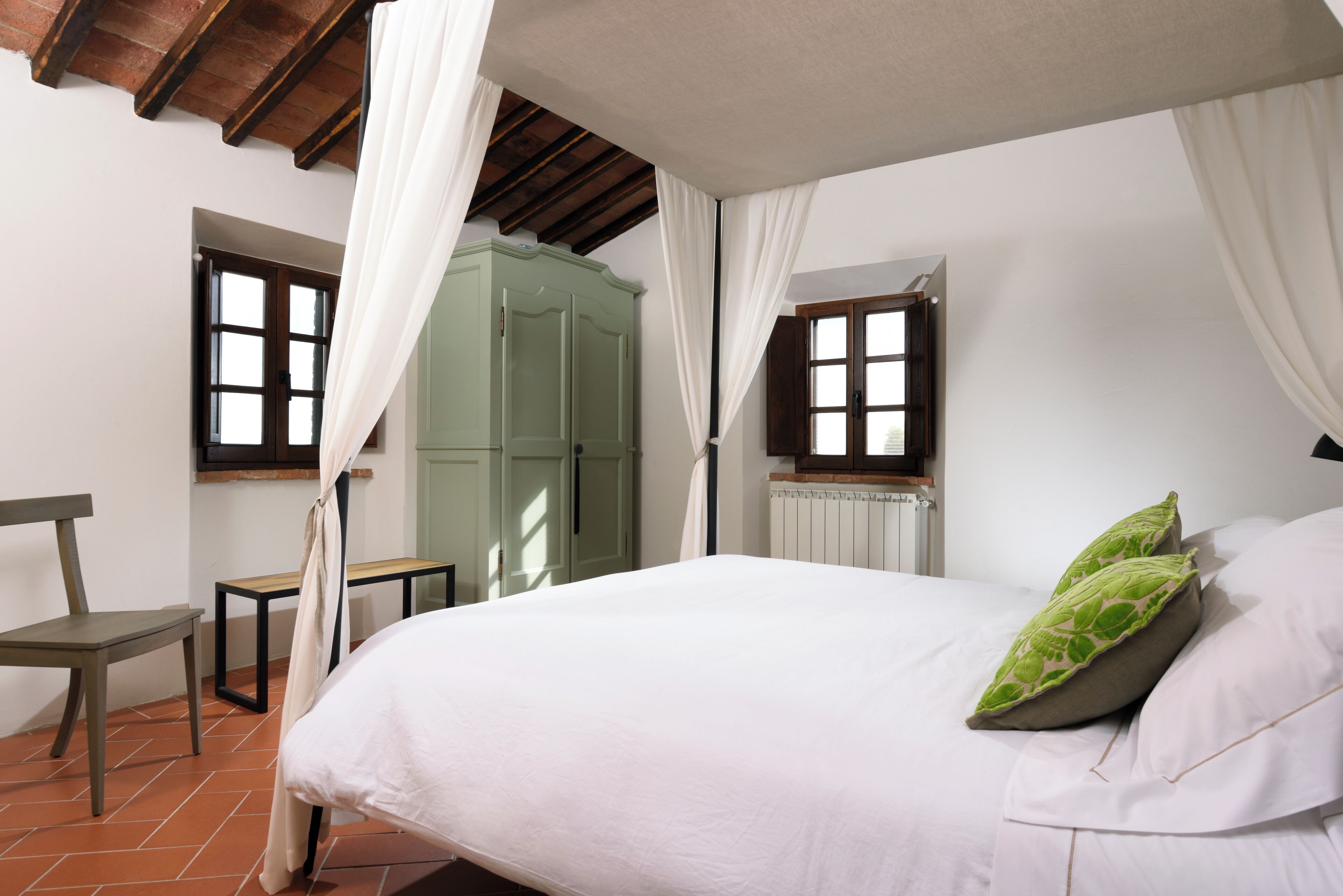 A bedroom with a bed, a chair, a table, and a wardrobe.