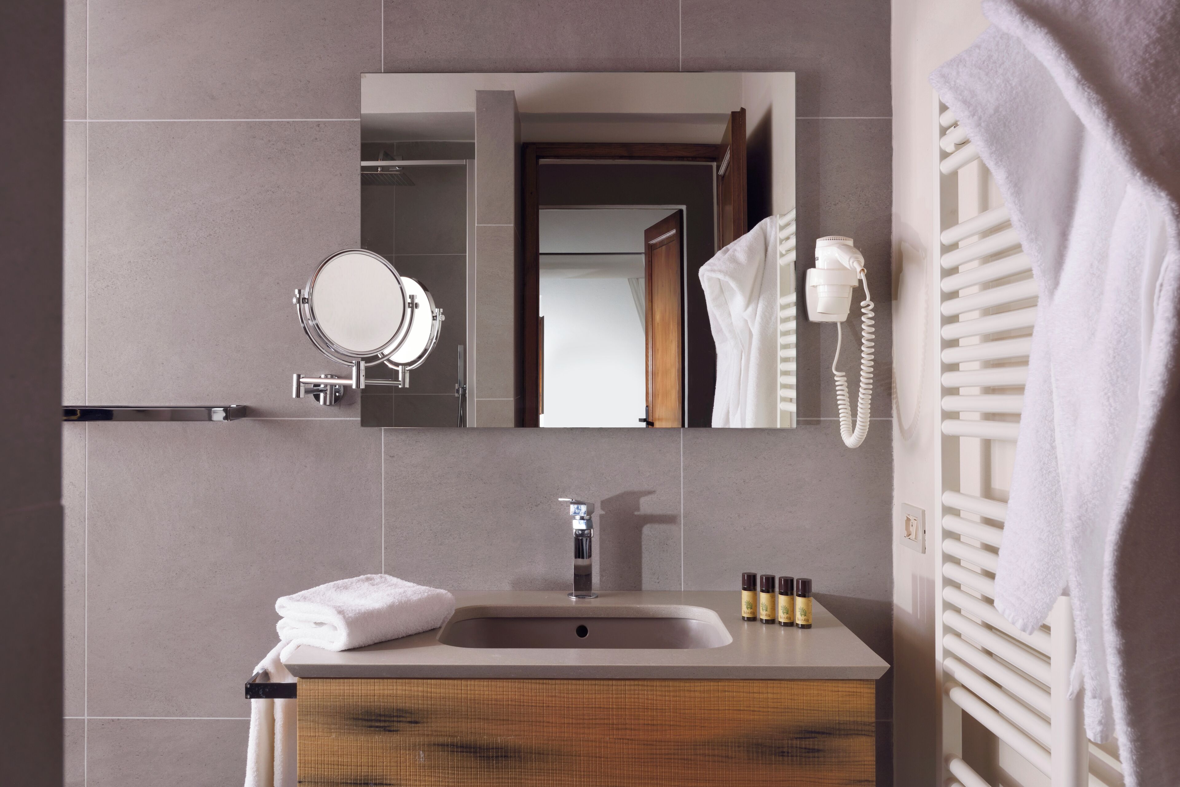 A modern bathroom with a large mirror, a sink, and a towel rack.
