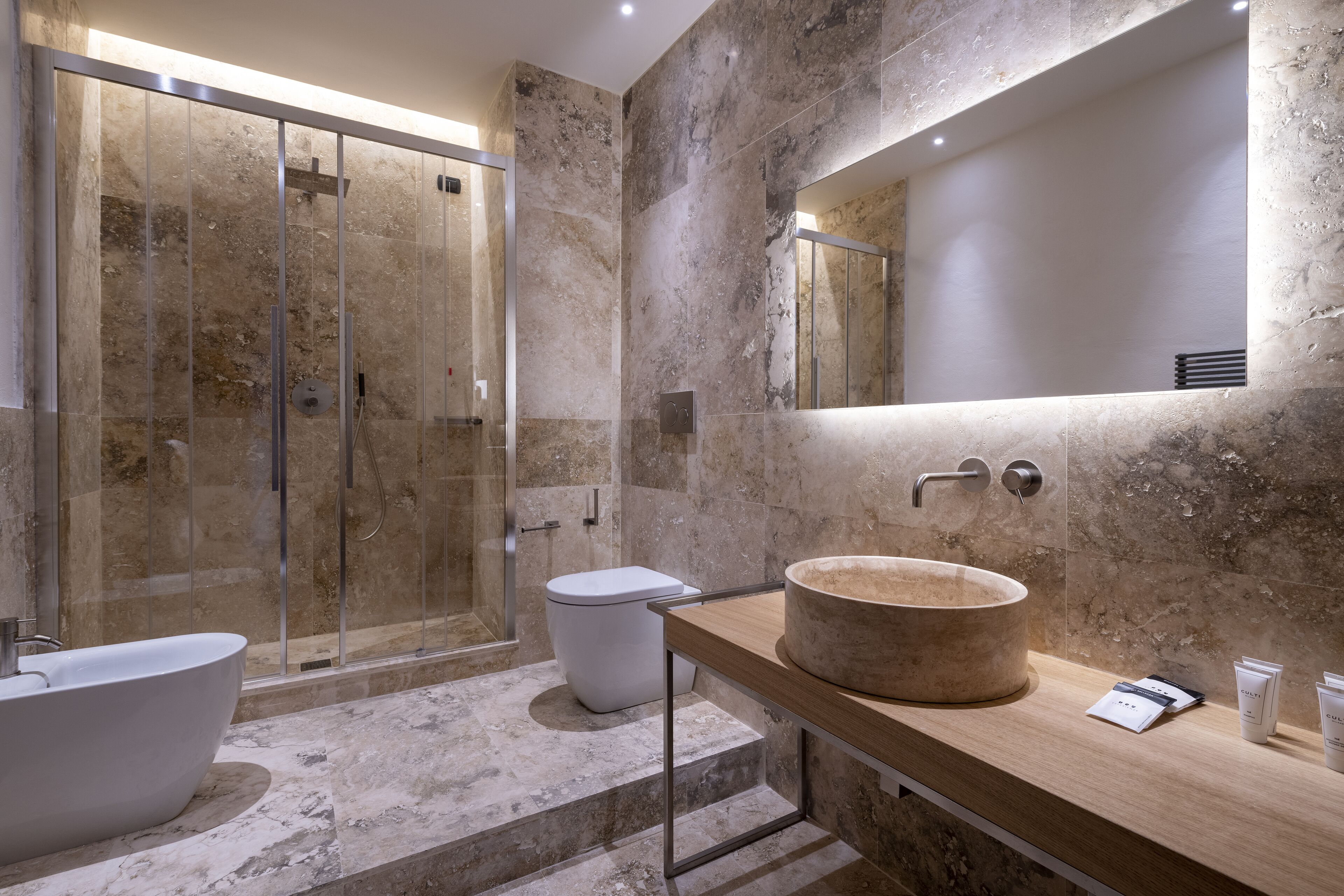 Ein modernes Badezimmer mit freistehender Badewanne, einem großen Spiegel und einer Dusche mit Marmorverkleidung.