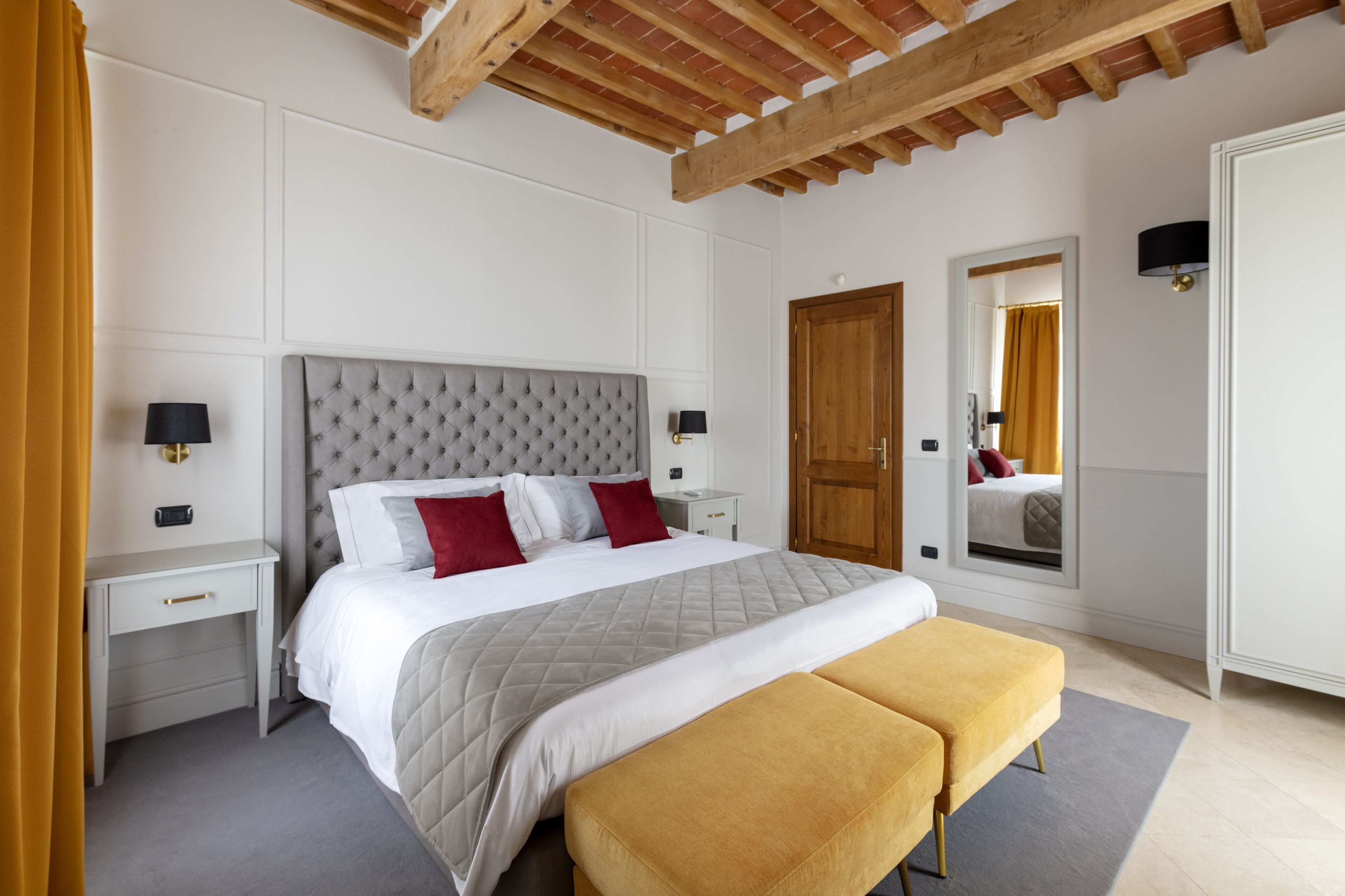 Un dormitorio con una cama grande, dos mesitas de noche, un armario y un espejo.