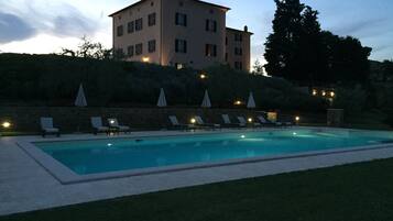 Una piscina al aire libre, sillones reclinables de piscina