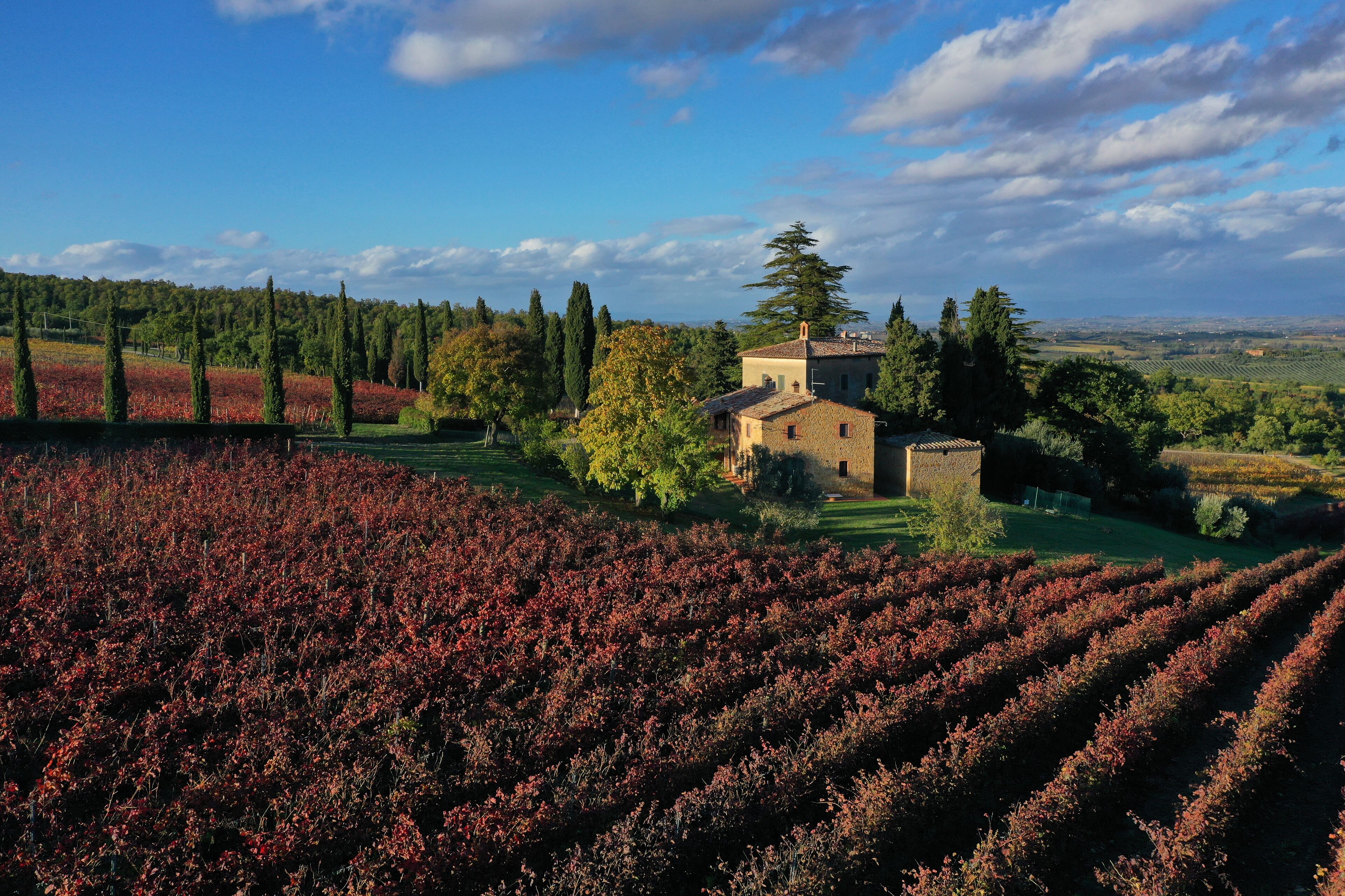 Un paysage rural avec un bâtiment en pierre, entouré de champs et d’arbres.