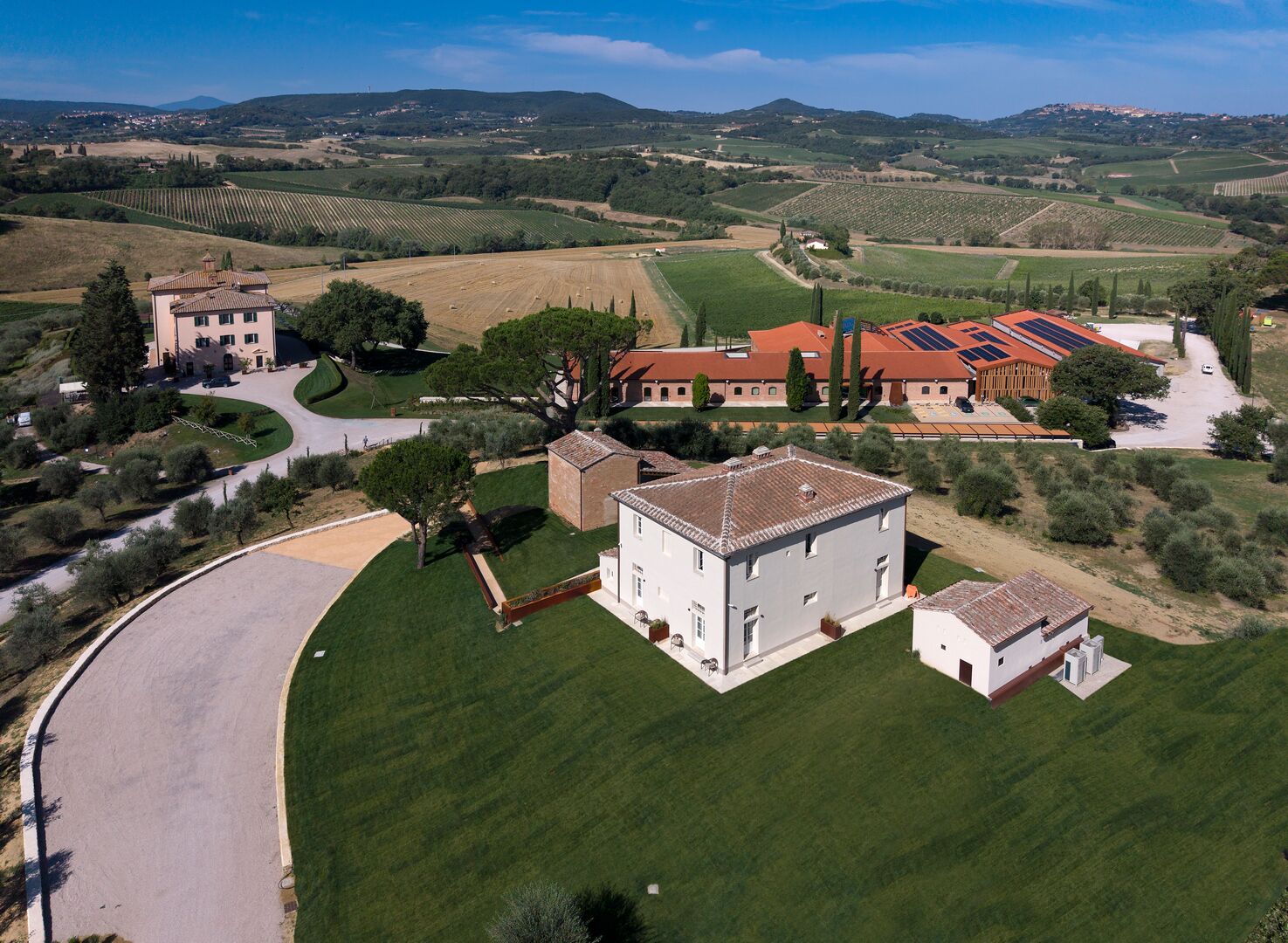 A rural property with a large building, a paved driveway, and surrounding fields.
