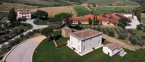 A rural property with a large building, a paved driveway, and surrounding fields.