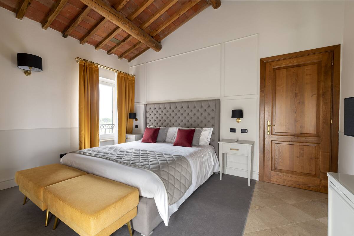 A bedroom with a bed, nightstands, a wooden door, and a window with curtains.