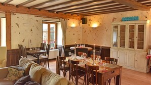 Un comedor con mesas y sillas de madera, un sofá y un armario con puertas de vidrio.