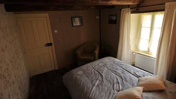 Un dormitorio con una cama, una silla, una puerta y una ventana con cortinas.