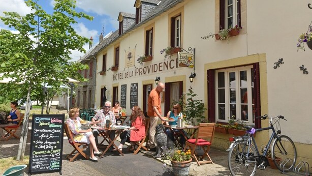 Un restaurante con terraza, un cartel que dice "Hotel de la Providence" y una bicicleta estacionada afuera.