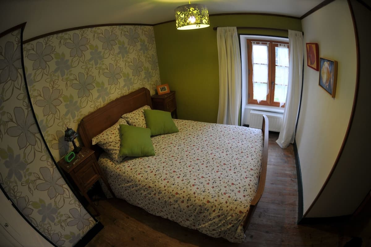Un dormitorio con una colcha de estampado floral, un cabecero de madera y una mesita de noche con lámpara.