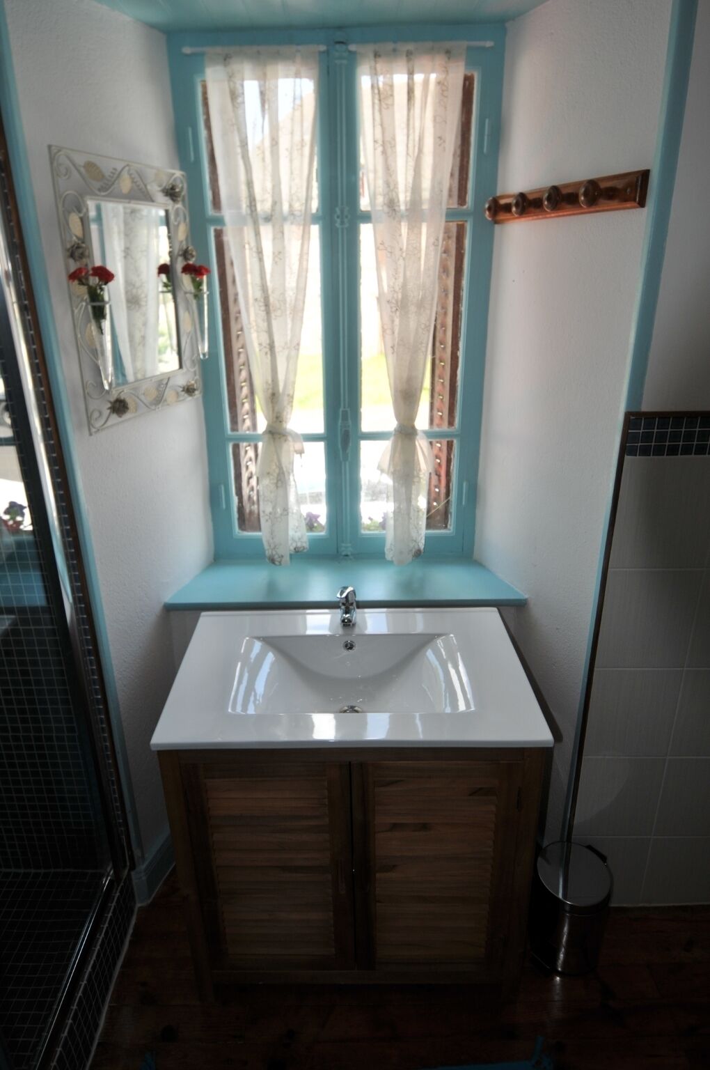 Ein Badezimmer mit Fenster, Waschbecken und Spiegel.
