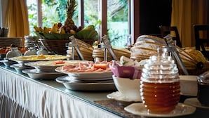Un bufé con diversos alimentos, entre ellos frutas, carnes y un tarro de miel.