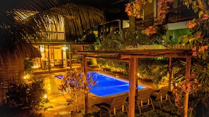 Un área de piscina con sillas de descanso y una estructura de techo de paja.