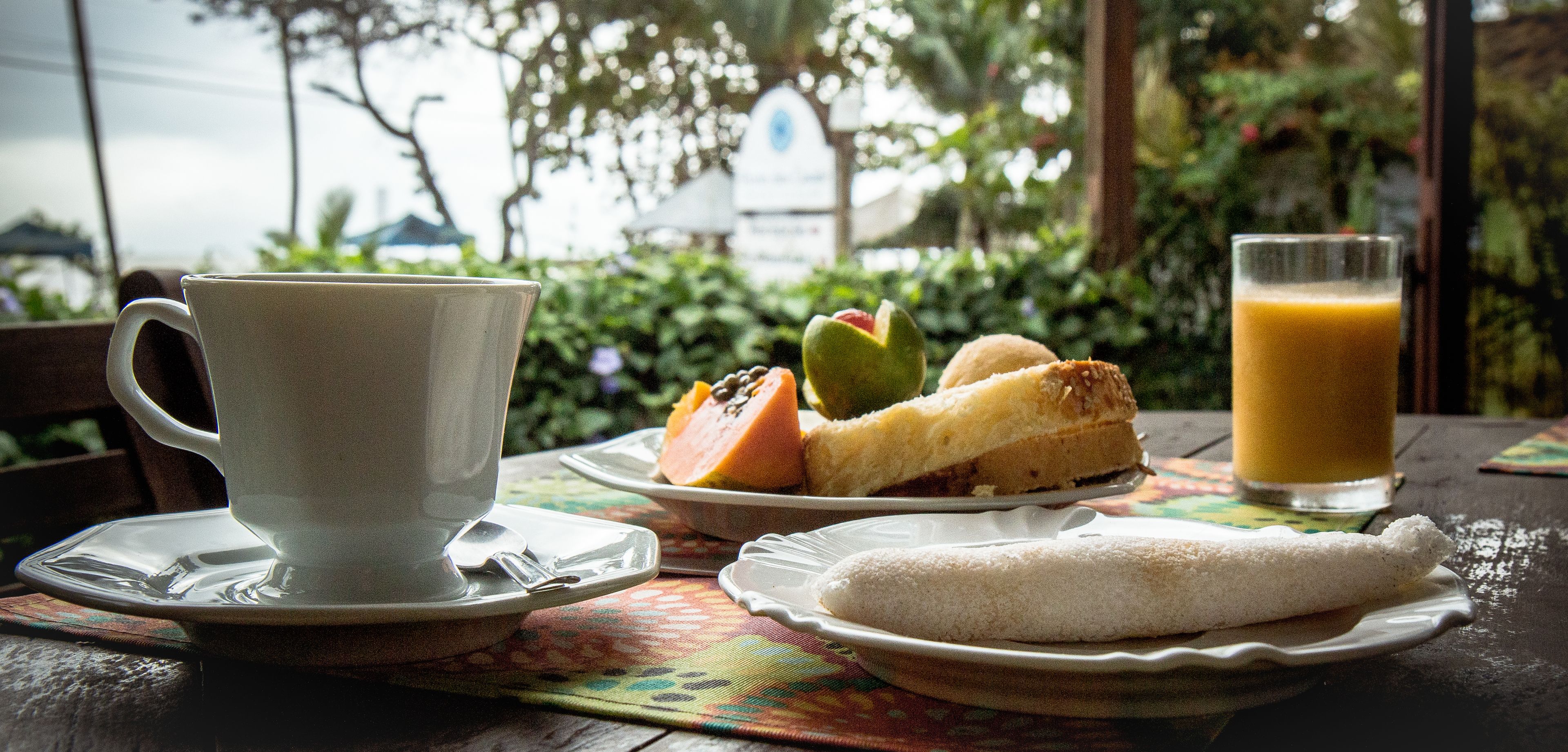 A table with a cup, a plate with food, and a glass of juice.