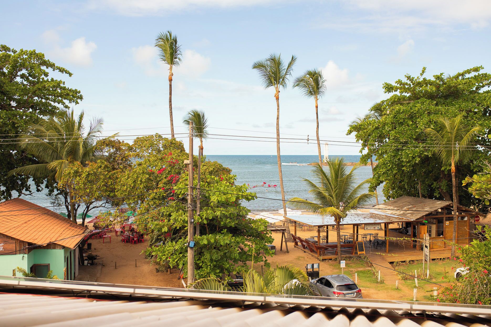 A coastal view with a beachside restaurant, palm trees, and a clear sky.