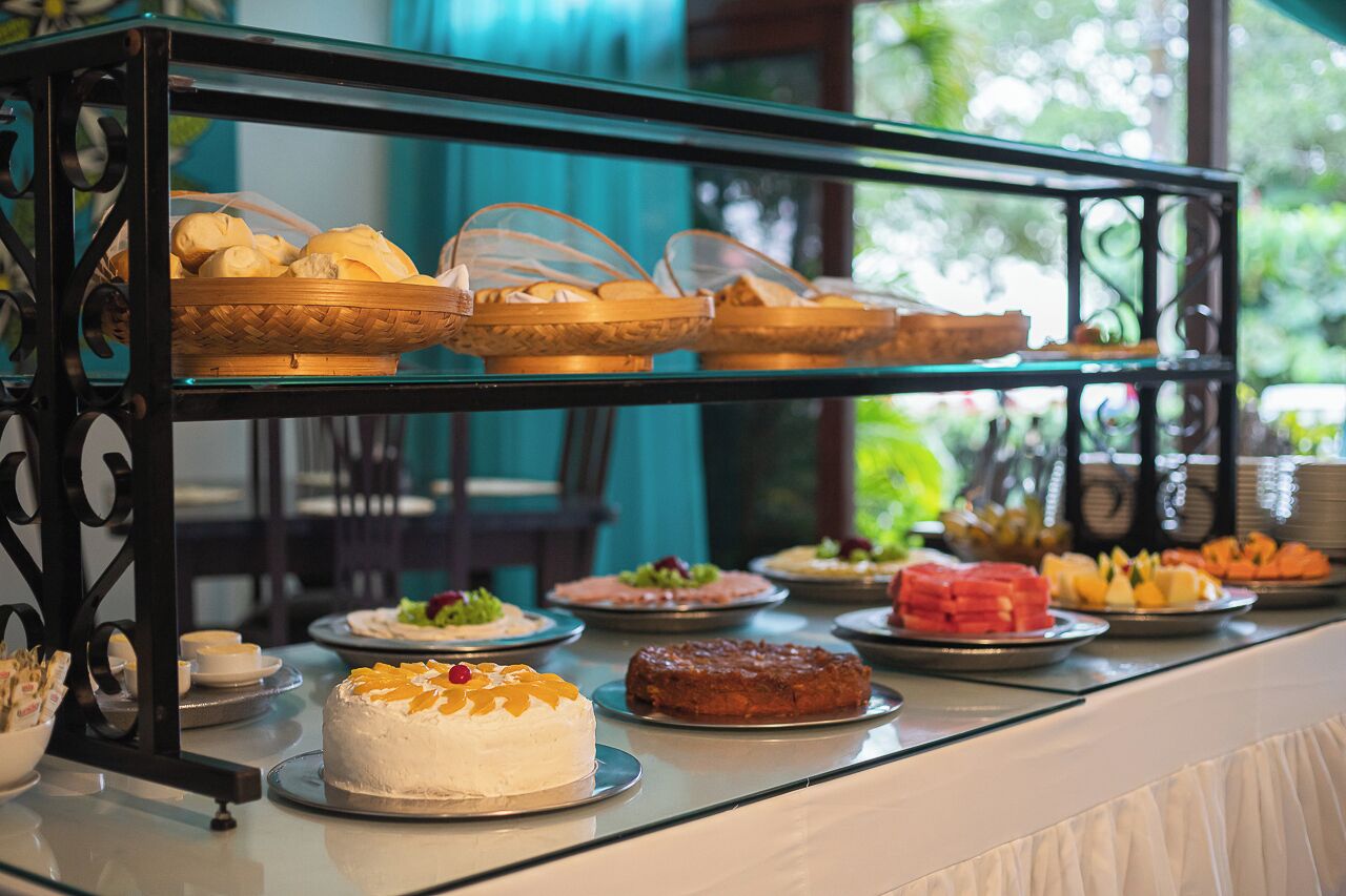 Una mesa de buffet con diversos alimentos, entre ellos, un pastel, pan y fruta.