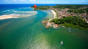 Vista aérea de un pueblo costero con playa, barcos y abundante vegetación.