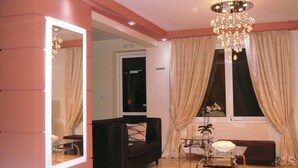 A modern living room with a black sofa, a glass coffee table, and a chandelier. - Avra Hotel (Lefkada)