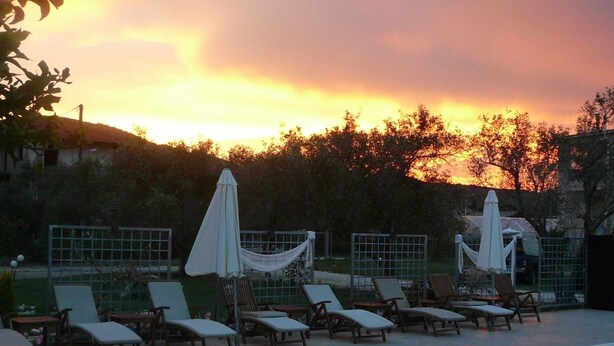 A swimming pool with lounge chairs and umbrellas, surrounded by a fence and trees. - Avra Hotel (Lefkada)