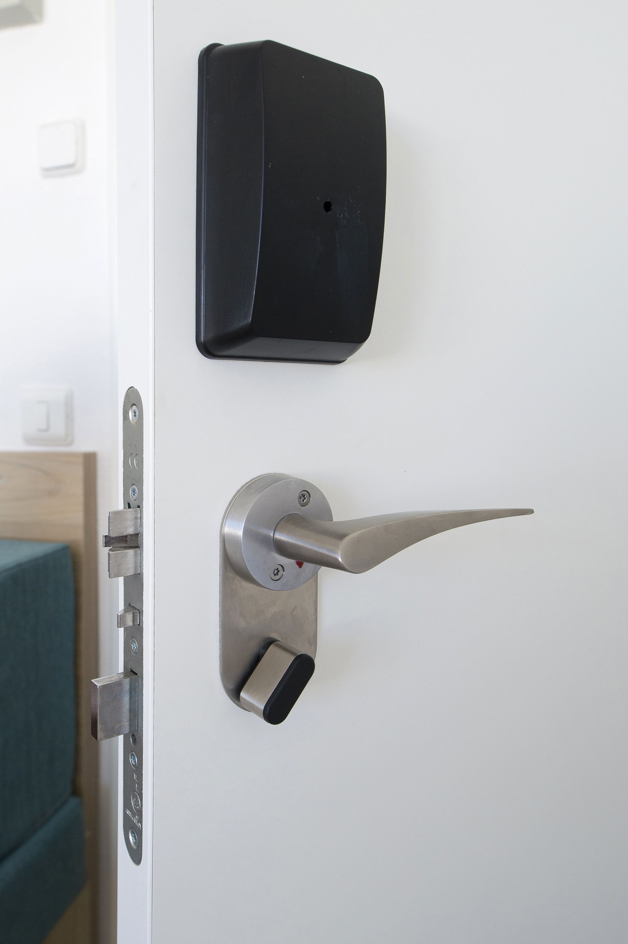 A modern door with a metallic handle and a black intercom mounted on the wall.