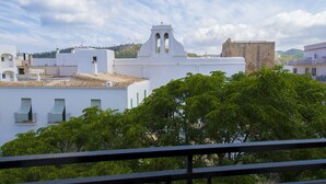 A white building with a bell tower and a balcony. - Apartamentos Tramuntana (Sant Antoni de Portmany)